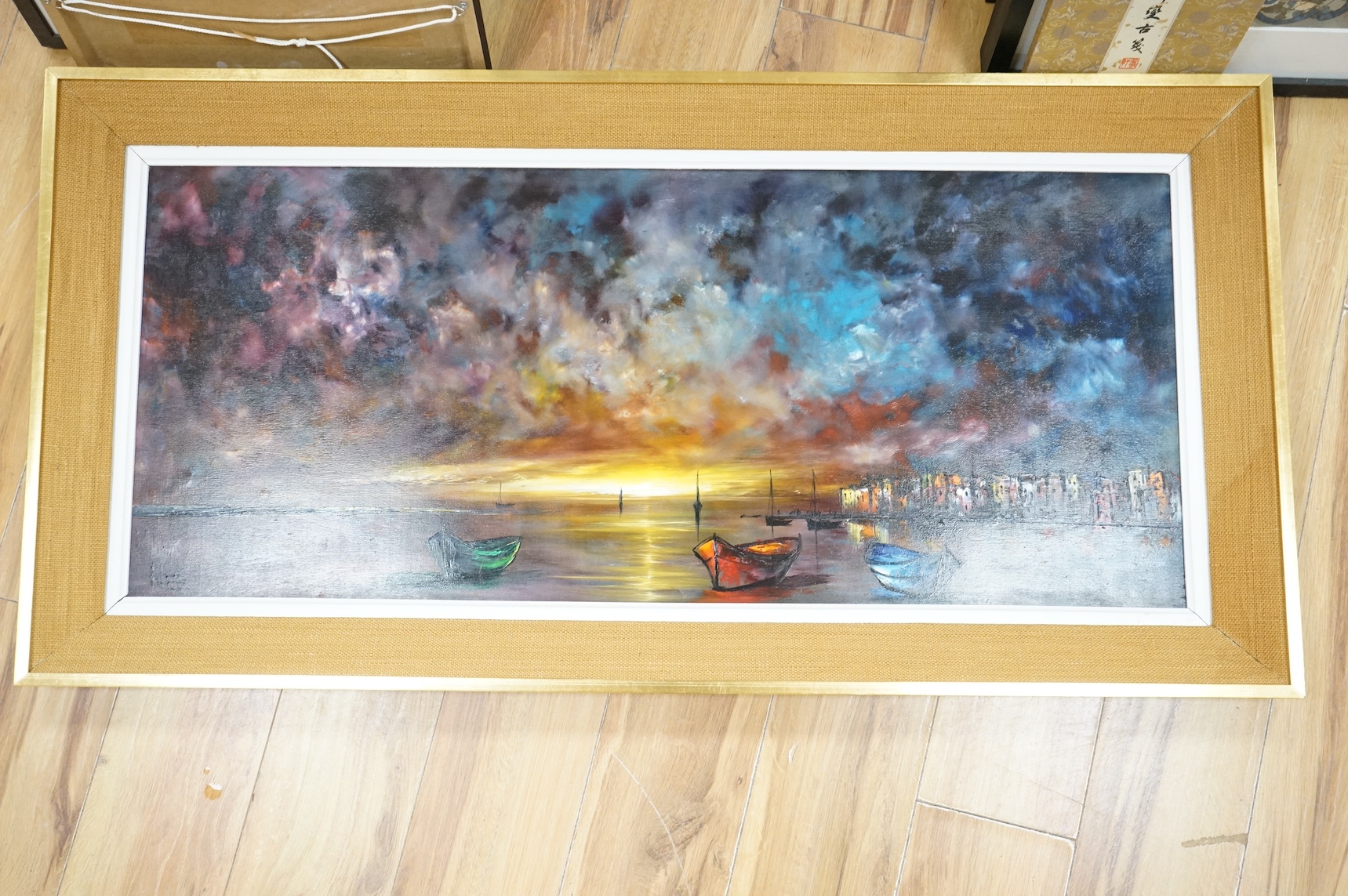 Modern and decorative oil on board, Beached fishing boats before a harbour, 44 x 105cm. Condition - good